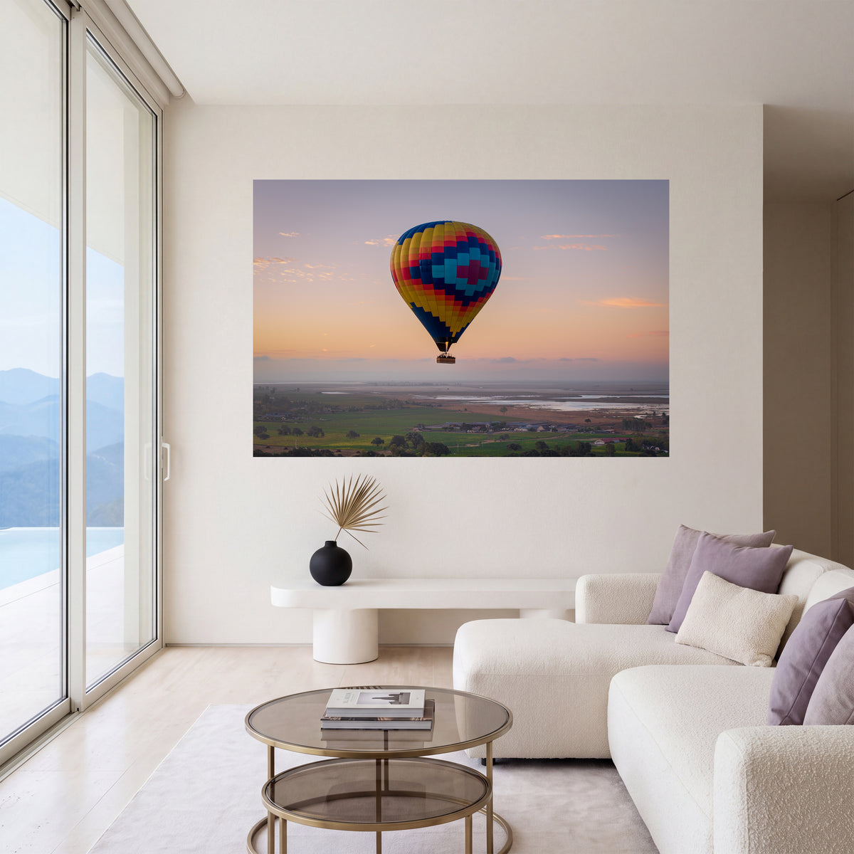 Carried by Light, a colorful hot air balloon photograph at sunrise, displayed as large-scale wall art in a serene contemporary living room.
