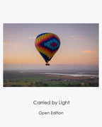 Collection card for Carried by Light, an open-edition photograph of a colorful hot air balloon floating above the Sonoma landscape at sunrise.