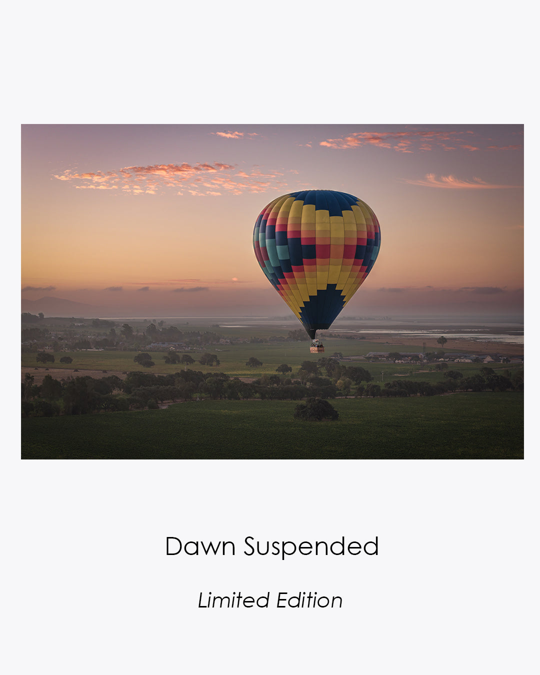 Colorful hot-air balloon drifting above misty Sonoma vineyards beneath a softly glowing dawn sky.
