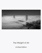 The Weight of Air, a black-and-white aerial view of the Golden Gate Bridge emerging through rolling San Francisco fog.