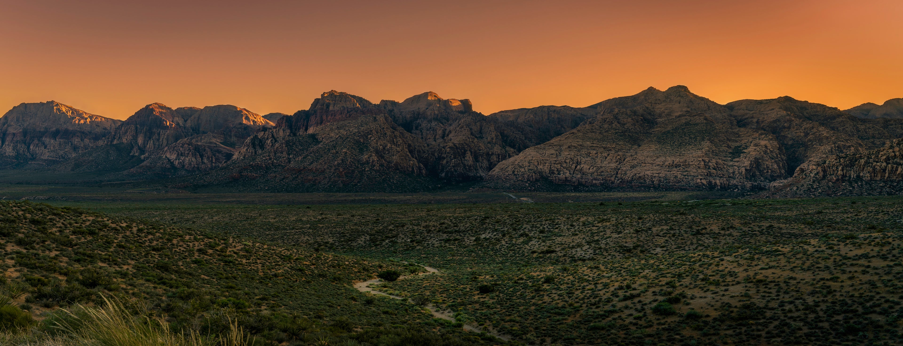 The final warm light of sunset illuminating the mountains and desert landscape of Red Rock Canyon, Nevada.