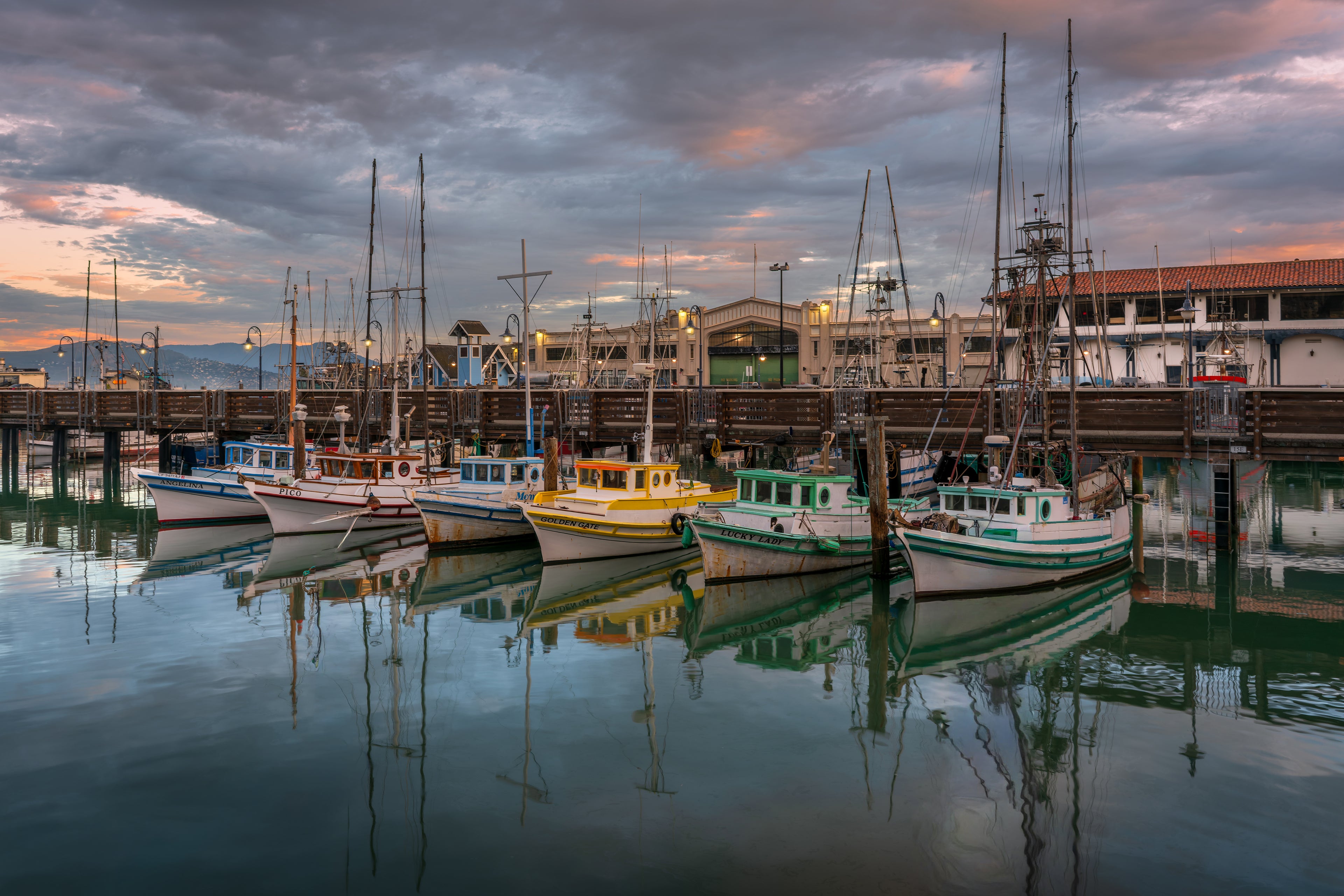 Boats and their reflections glowing in the blue-hour stillness of San Francisco as the last light of night begins to fade.