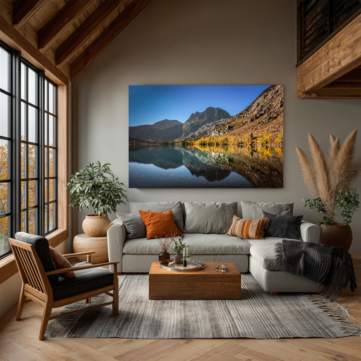 Autumn Echo displayed above a gray sectional sofa in a living room with exposed wood beams, tall windows, and warm autumn accents.