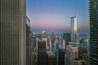 Aerial view of the Chicago skyline at sunrise, photographed by drone between two towering buildings beneath a blue, lavender, and rose sky.