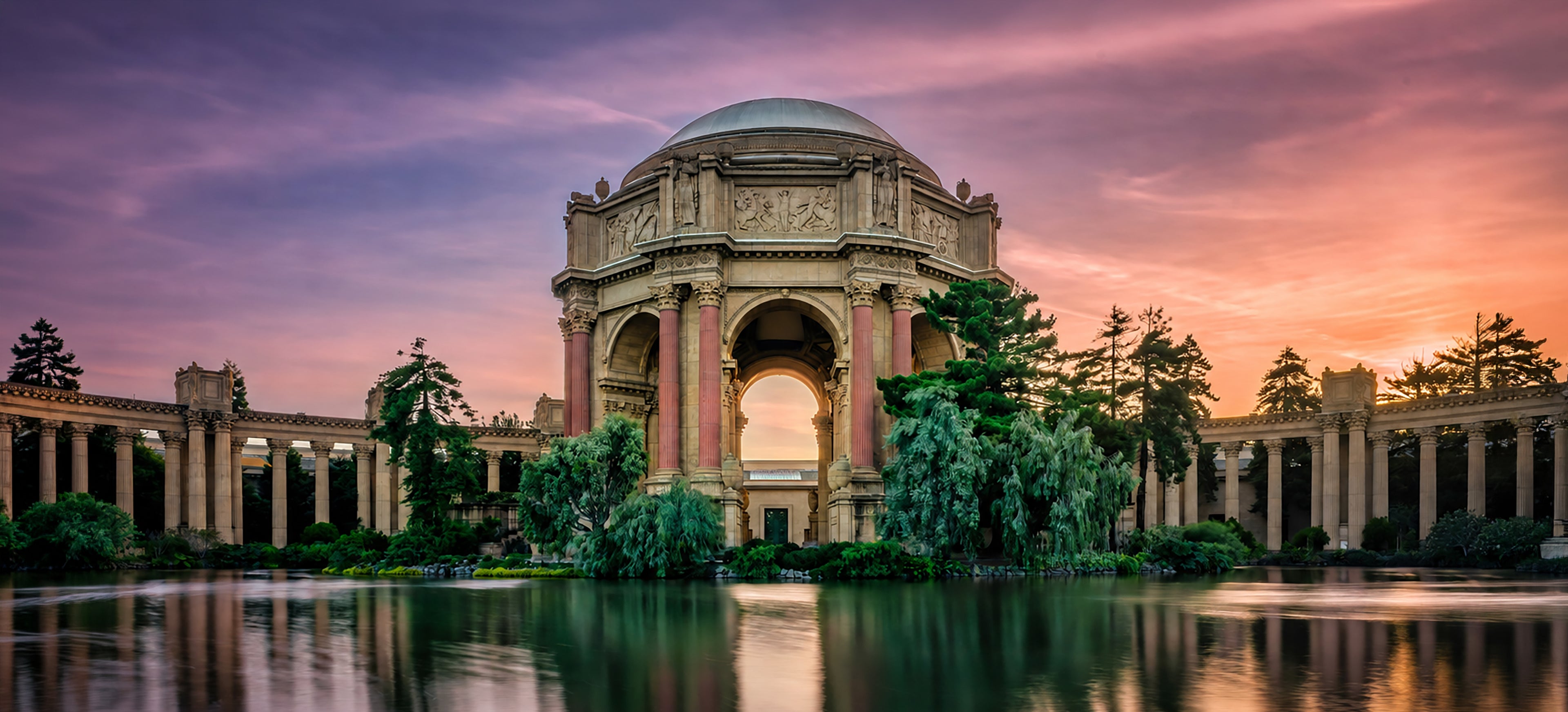 Palace of Fine Arts reflected in still water beneath a luminous pink and lavender sunset in San Francisco