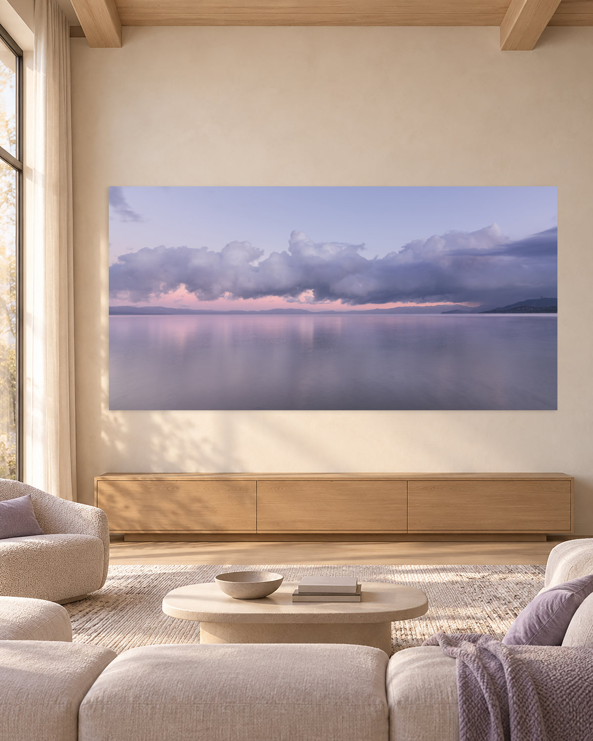 Above and Below, a panoramic Lake Tahoe sunrise photograph displayed above a light oak console in a serene, neutral living room.