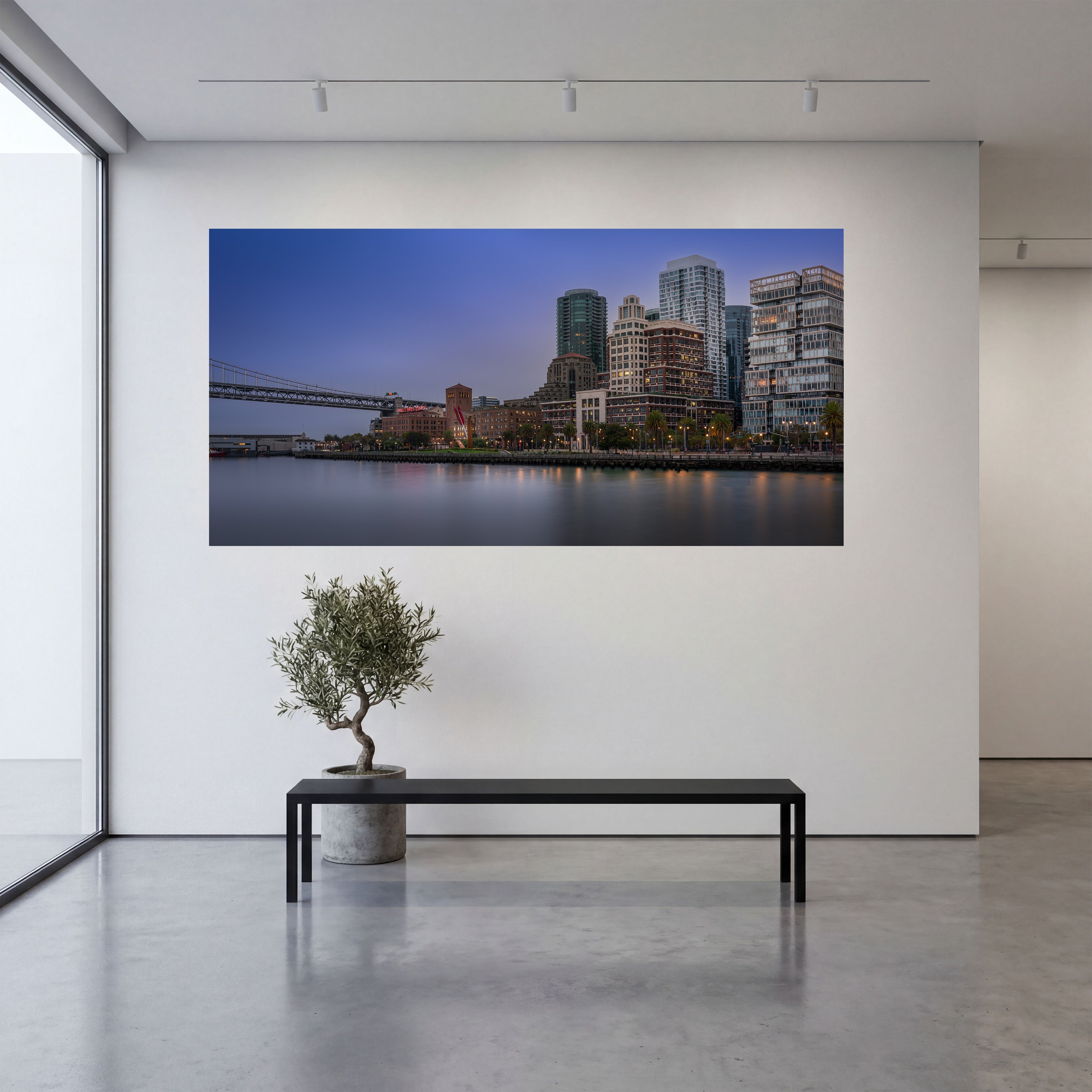 Large panoramic acrylic print of Signs of Morning displayed above a black bench in a minimalist modern interior with white walls and concrete floors.