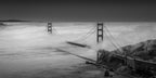 Large black-and-white panoramic Golden Gate Bridge photograph displayed above a cream sofa in an elegant neutral-toned lounge.