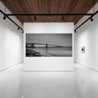 Large panoramic print of Where Certainty Ends, showing the Golden Gate Bridge fading into fog, displayed on a white wall in a contemporary gallery.